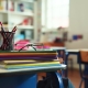 Student desk with pencil and standardized test booklet in soft natural light, empty classroom setting.
