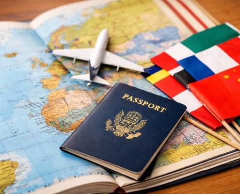 Passport, small airplane model, and international flags placed on an open world map, symbolizing global travel and international education opportunities.