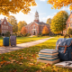 A serene autumn boarding school campus with red-brick academic buildings in the background, a tree-lined pathway with two suitcases, and in the foreground a stack of books, an open notebook with glasses, and a backpack resting on fallen leaves.