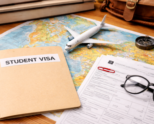 Student visa folder and I-20 paperwork on a world map with a model airplane, glasses, and travel accessories on a wooden desk