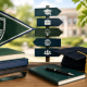 Graduation cap, books, globe, and school crest on a desk with a campus background, symbolizing academic achievement and alumni success.