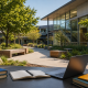Modern school courtyard with outdoor study setup, featuring books and a laptop on a desk in a bright, landscaped campus setting.